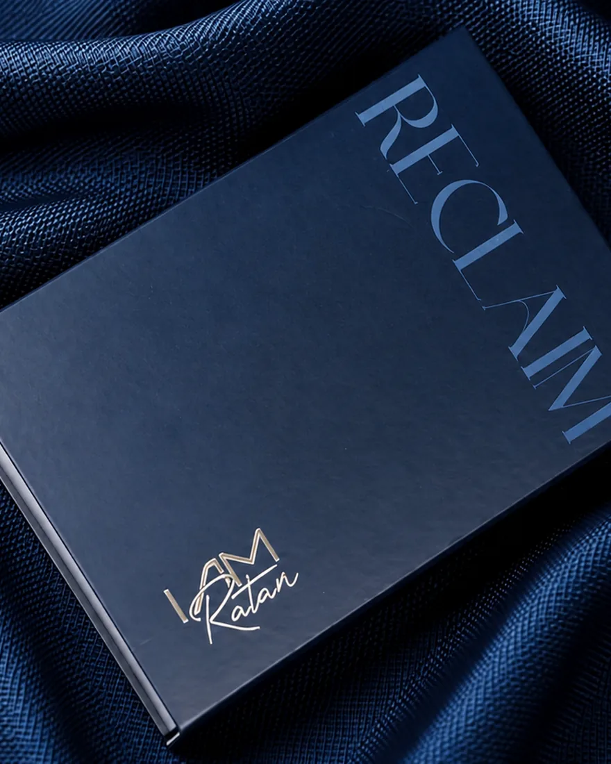 The house box in navy, RECLAIM foiled across the lid and the I Am Ratan signature beneath
